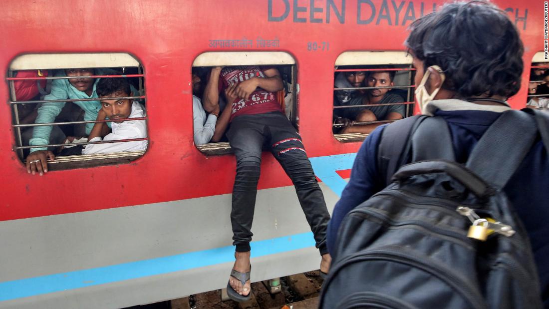 A migrant worker attempts to board an overcrowded train in Mumbai.