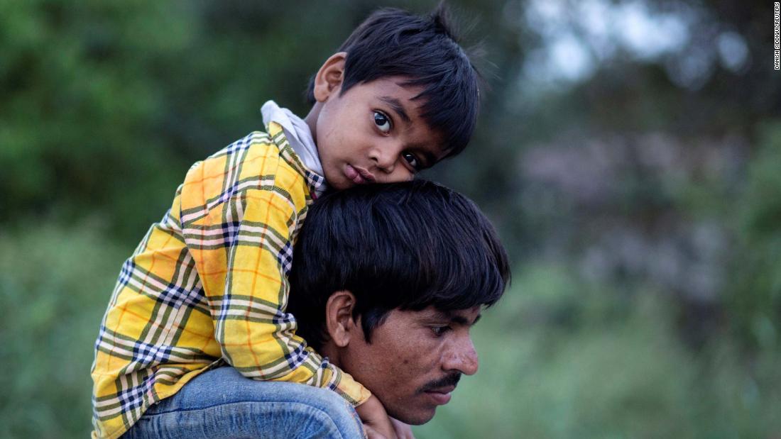 A migrant worker carries a child as they walk along a road in New Delhi.