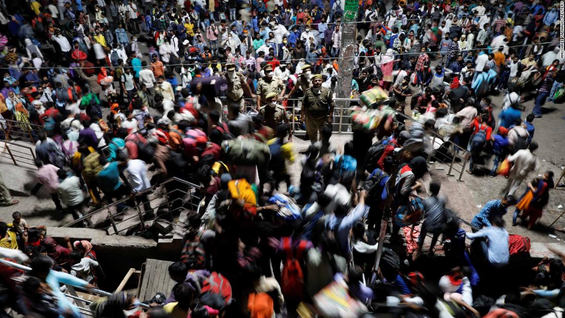 Police officers stand by as migrant workers scramble inside a bus station in Ghaziabad, India, on Saturday, March 28.