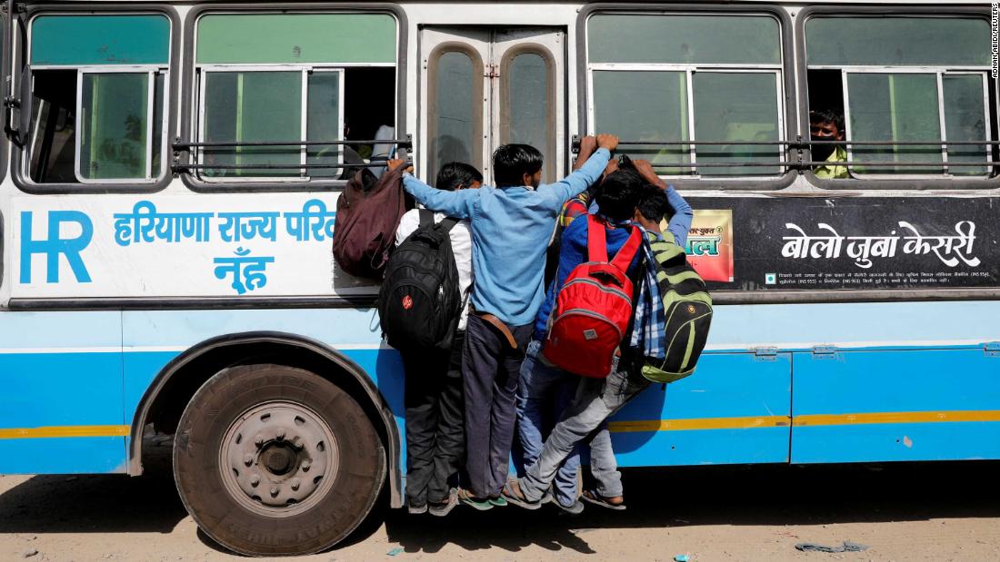 People hang on to a door of a moving bus on the outskirts of New Delhi.