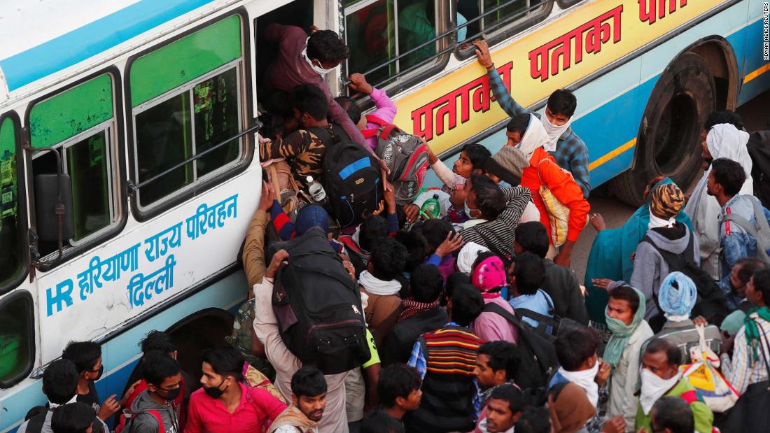 Migrant workers try to board a crowded bus in Ghaziabad on Sunday, March 29. The state governments of Uttar Pradesh, Bihar and Haryana arranged for hundreds of buses to ferry migrants home, causing chaotic scenes as thousands descended upon stations trying to claw their way onto buses.