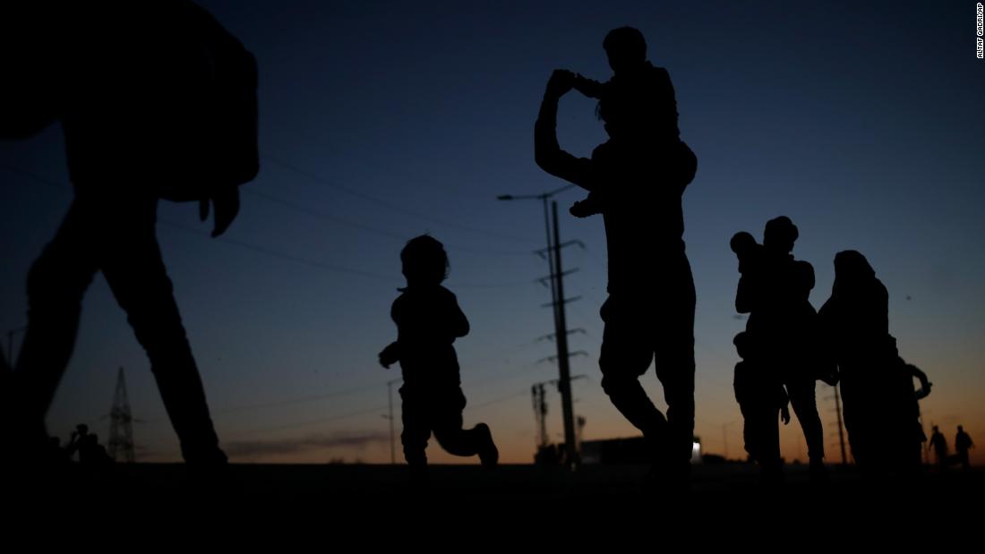 A laborer's family is silhouetted in New Delhi as they journey to their village by foot.