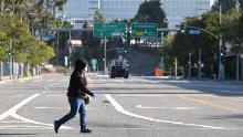 A woman wears a mask as she crosses an empty street near the Los Angeles Convention Center.