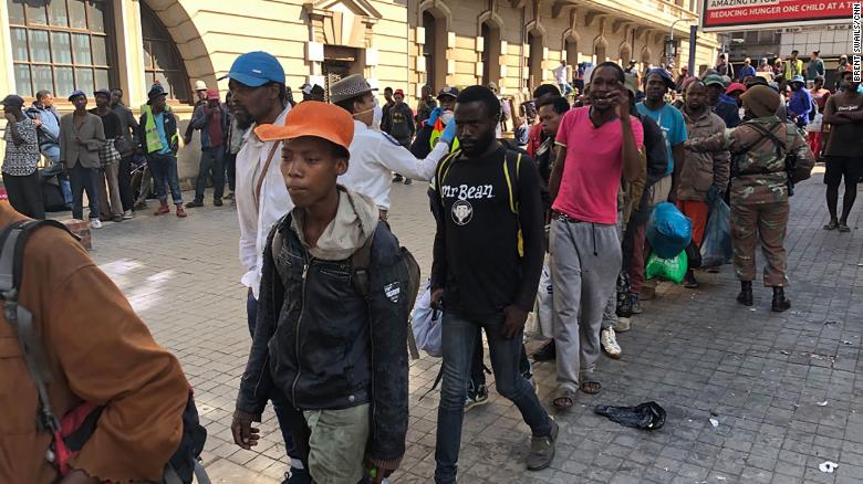 Lines of homeless South Africans await police transport to temporary shelters in downtown Johannesburg.