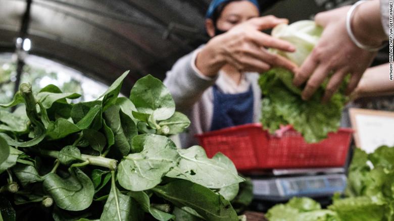 A woman wearing a facemask sells vegetables at a community farm in Hong Kong on March 18.