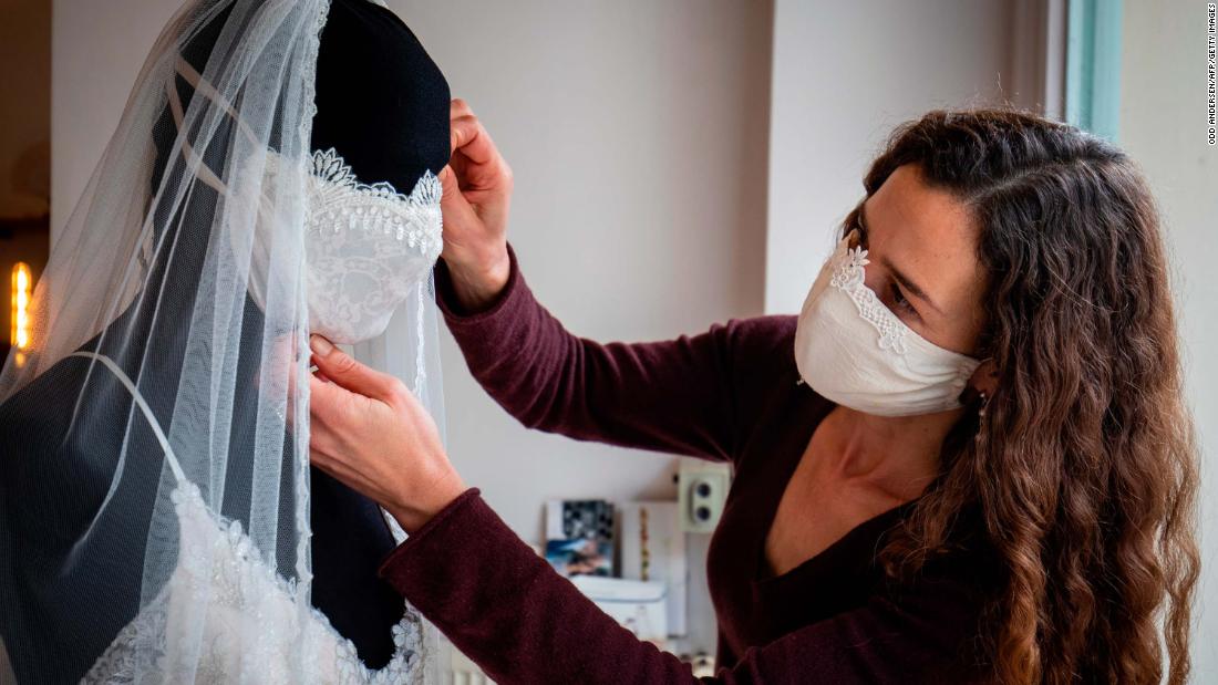 Designer Friederike Jorzig adjusts a mannequin wearing a wedding dress and a face mask at her store in Berlin on March 31, 2020.