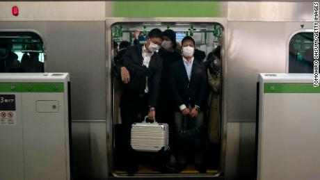 Commuters wearing face masks ride on a train on March 26, 2020 in Tokyo, Japan. 