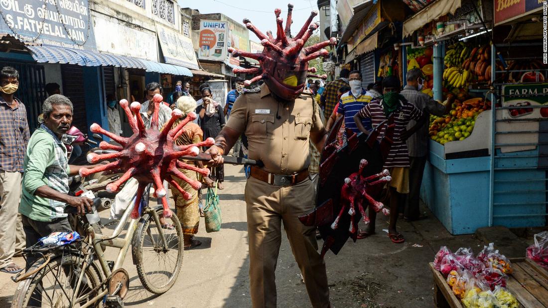 A police officer wearing a coronavirus-themed outfit walks in a market in Chennai, India, to raise awareness about social distancing.