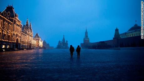 Two police officers patrol an almost empty Red Square, with St. Basil&#39;s Cathedral, center, and Spasskaya Tower and the Kremlin Wall, right, at the time when its usually very crowded in Moscow, Russia, Monday, March 30, 2020.