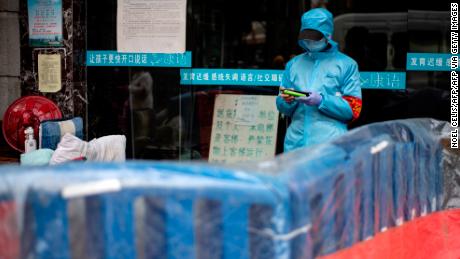 A community volunteer uses her mobile phone near a barrier separating a residential compound in Wuhan on April 2.