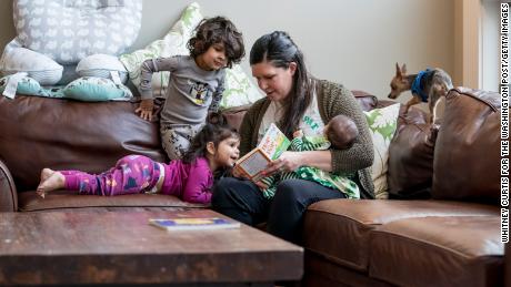 Katie Patel holds her 3-month old daughter, Lucy, as she reads to her son Parker, 3, and daughter, Isla, 1, before bedtime at their home in Creve Coeur, Missouri, on March 17, 2020. (Photo by Whitney Curtis for The Washington Post/Getty Images)