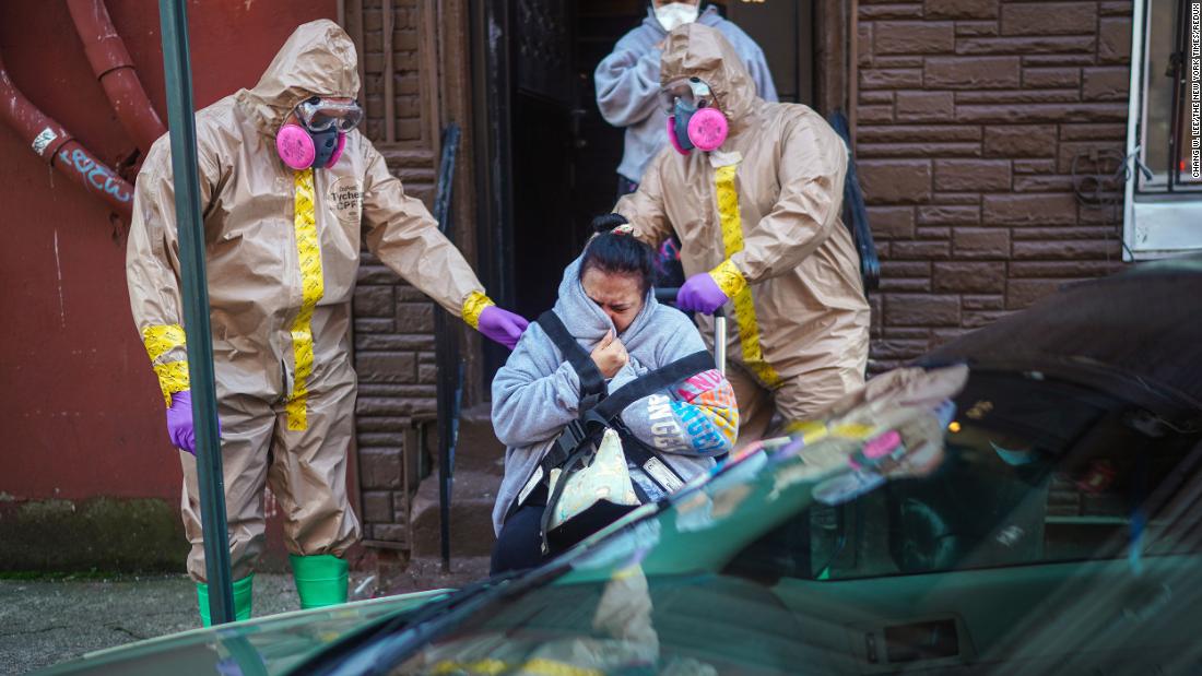 A woman suspected of having coronavirus is helped from her home by emergency medical technicians Robert Sabia, left, and Mike Pareja, in Paterson, New Jersey.