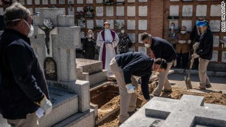 A priest and relatives pray as a victim is buried at the cemetery on March 28.