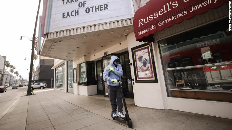 A man wears gloves and a bandanna across his face while riding a scooter on March 18, 2020 in Beverly Hills, California.