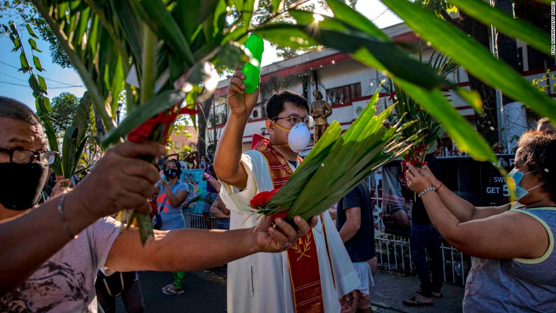 A Catholic priest sprinkles holy water on devotees during Palm Sunday celebrations in Quezon City, Philippines, on April 5, 2020.