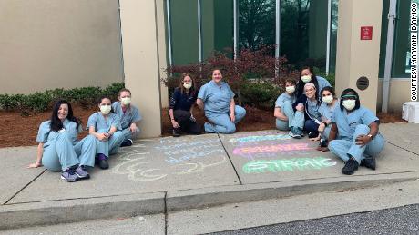 Northside Hospital nurses gather around a supportive message chalked on the sidewalk in front of the emergency room entrance.