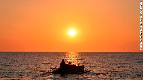 This photo taken on February 14, 2020 shows a Filipino fisherman sailing off at sunset from the coast of Bacnotan, La Union province, in northwestern Philippines facing the South China Sea. (Photo by Romeo GACAD / AFP) (Photo by ROMEO GACAD/AFP via Getty Images)