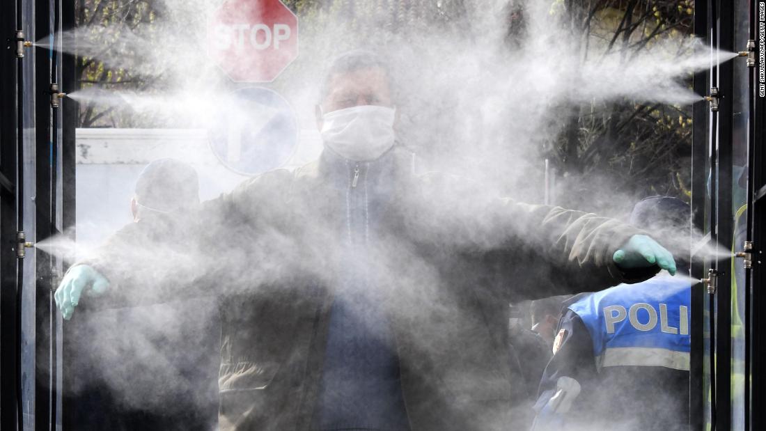 A man is sprayed with disinfectant prior to going to a market in Tirana, Albania.