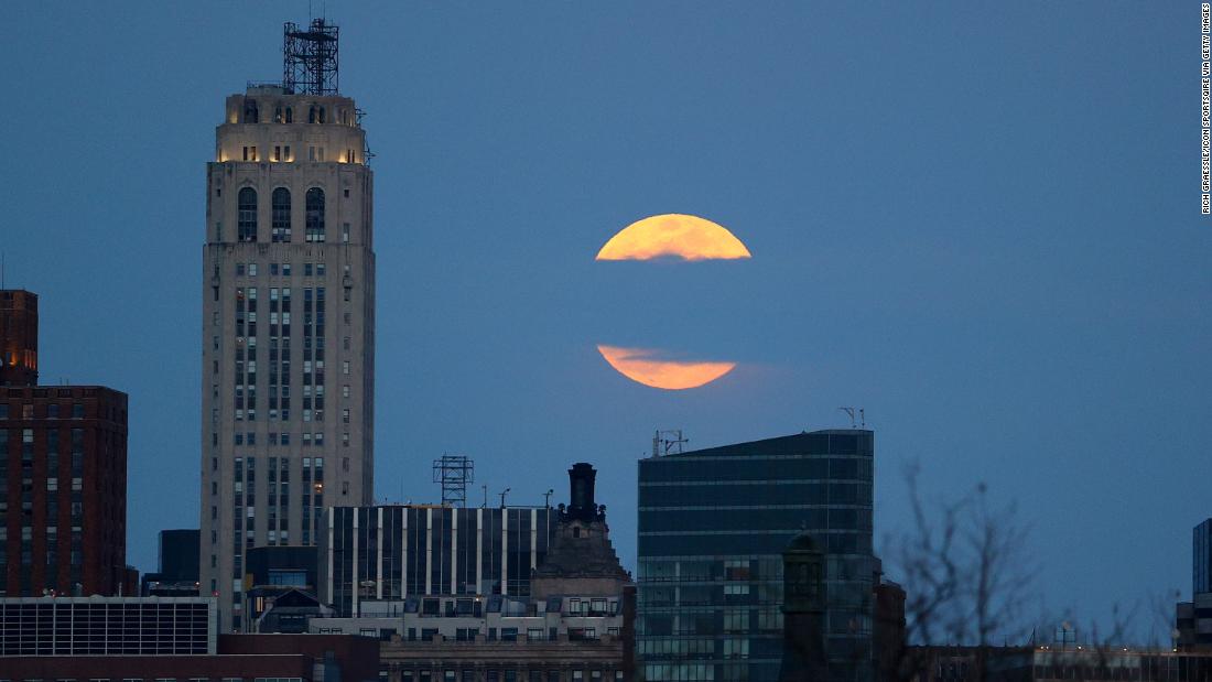 The moon rises behind New York City.