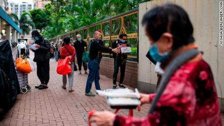 Chu Kin Lik, 61, makes sure people keep their distance as they wait for dinner at Impact HK's meal service on Tuesday, April 7