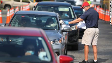 Miguel Diaz, who works for the Florida city of Hialeah, hands out unemployment applications to people in their vehicles in front of a library Wednesday. 