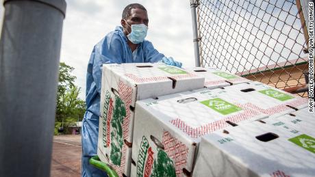 A worker wearing a protective mask and gloves moves boxes of produce to a refrigerated trailer in Jackson, Mississippi. 