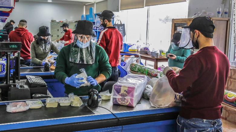 Employees work while wearing protective face shields and gloves at a store in the northern Lebanese city of Batroun on March 23.