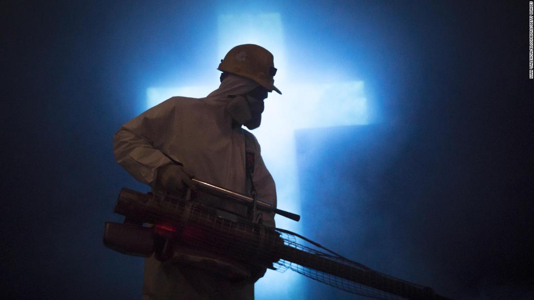 A worker disinfects a carved cross at the Salt Cathedral in Zipaquira, Colombia, on April 8, 2020.