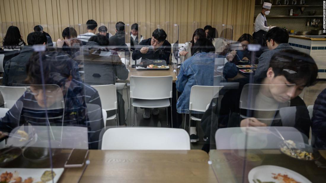 Employees of Hyundai Card, a credit card company, sit behind protective screens as they eat in an office cafeteria in Seoul, South Korea, on April 9, 2020.