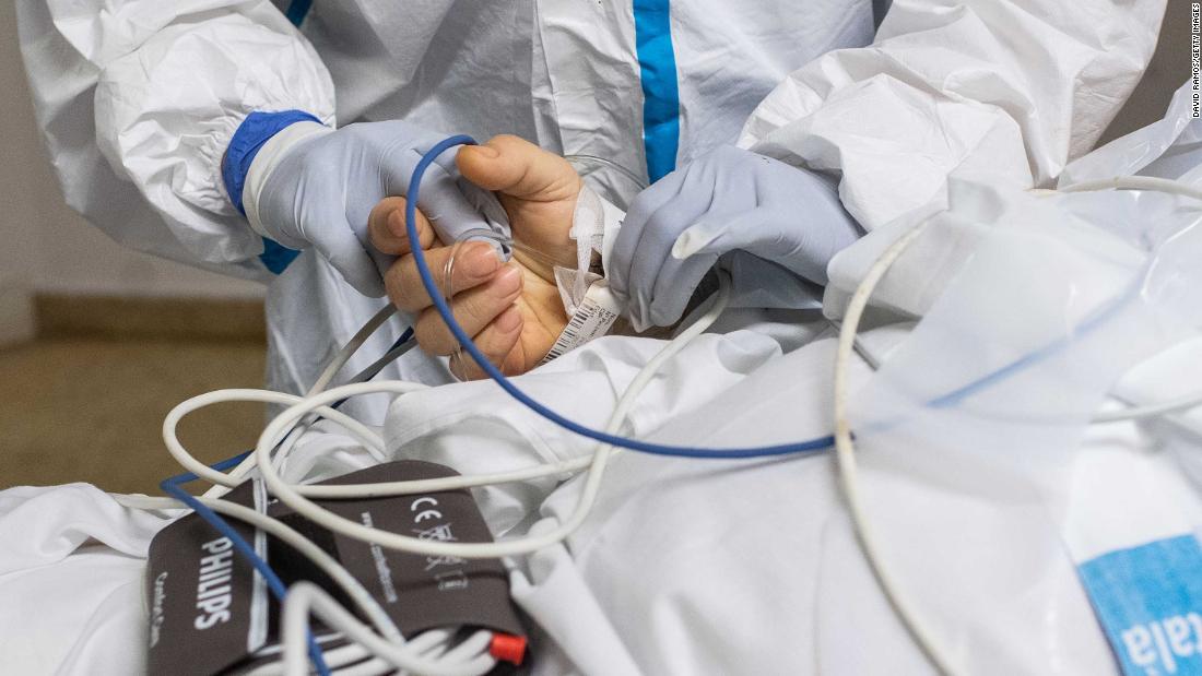 A health care worker holds the hand of a coronavirus patient being moved at a hospital near Barcelona, Spain, on April 9.