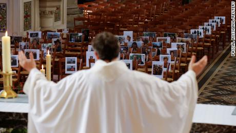 Priest Xavier Lemble realiza uma missa de Páscoa com fotografias de paroquianos nos bancos em Bethune, França, a 12 de Abril.