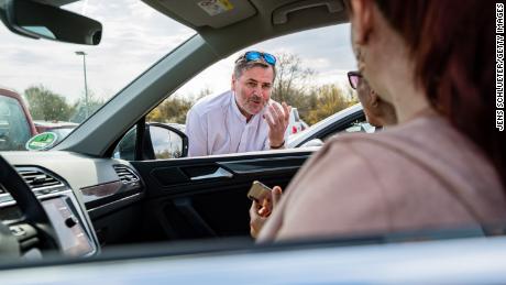 Pastor Christoph Knoll begroet parochianen voorafgaand aan een dienst op een parkeerplaats in Erfurt, Duitsland.