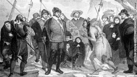 An illustration of Myles Standish and Pilgrims greeting a Native American at Plymouth Rock in 1620.