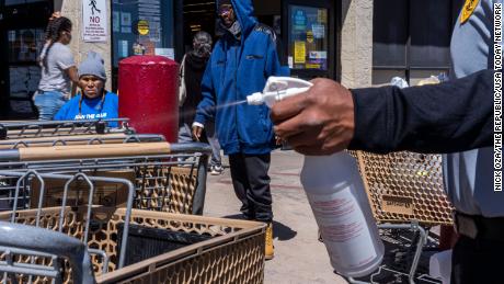 A Safeway security guard sprays bleach on a shopping cart on April 11, 2020, in Winslow, Arizona, where Navajos go to stock up on food and seek medical help.