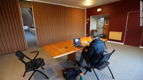 The Rev. Kelly Wadsworth sits alone in a parlor adjacent to the empty sanctuary at the Alki United Church of Christ in Seattle as she livestreams a sunrise service.