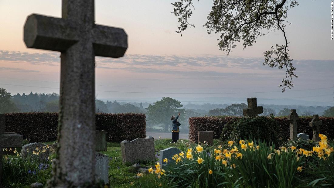 Priest-in-charge Angie Smith uses her phone to broadcast an Easter service from a churchyard in Hartley Wintney, England.