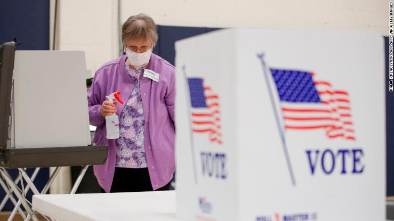 An election observer cleans voting booths during a Democratic presidential primary election at the Kenosha Bible Church gym in Kenosha, Wisconsin, on April 7, 2020.