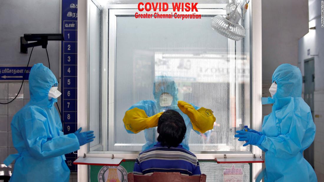 A doctor in a protective chamber tests a patient for coronavirus at a walk-in kiosk in Chennai, India.