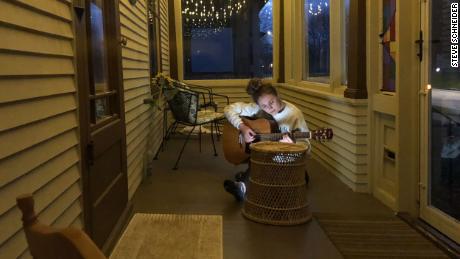 Steve Schneider&#39;s 18-year-old daughter plays her guitar on their porch in Sheboygan, Wisconsin