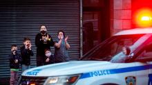 TOPSHOT - A family applauds in front of the Mount Sinai Hospital in Queens next to a police car to show gratitude to medical staff and essential workers working on the front lines of the coronavirus pandemic on April 13, 2020 in New York City. - New York's governor declared Monday that the "worst is over" for its coronavirus outbreak, despite deaths passing 10,000, as several states began devising a plan to reopen their shuttered economies. (Photo by Johannes EISELE / AFP) (Photo by JOHANNES EISELE/AFP via Getty Images)