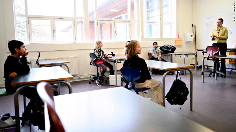 Denmark's Prime Minister, right, speaks to students sitting two meters away from each other during the reopening of Lykkebo School in Copenhagen.
