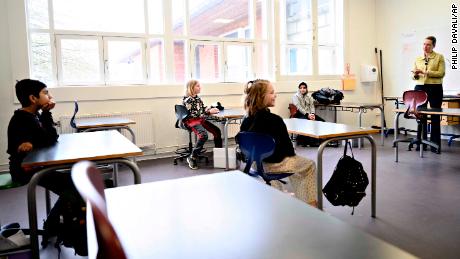 Denmark&#39;s Prime Minister Mette Frederiksen, right, speaks to students sitting two meters away from each other during the reopening of Lykkebo School in Copenhagen.