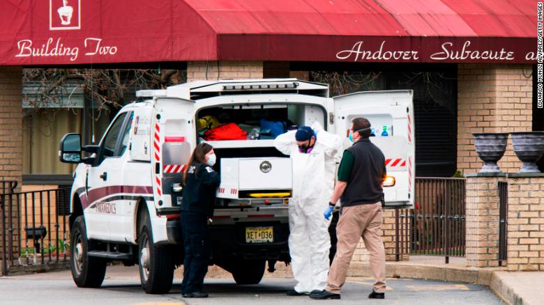 Medical workers put on masks and personal protective equipment while preparing to transport a body at Andover Subacute and Rehabilitation Center on Thursday in Andover, New Jersey.