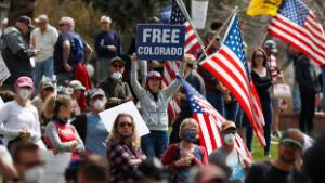 Protesters stand on the front lawn of the Sgtate Capitol during a protest against the stay-at-home order issued by Colorado Governor Jared Polis to stem the spread of the new coronavirus Sunday, April 19, 2020, in Denver. (AP Photo/David Zalubowski)