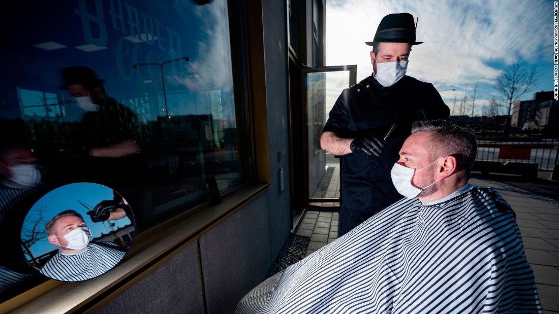 Abed Khankan cuts a customer&#39;s hair outdoors in Malmo, Sweden.