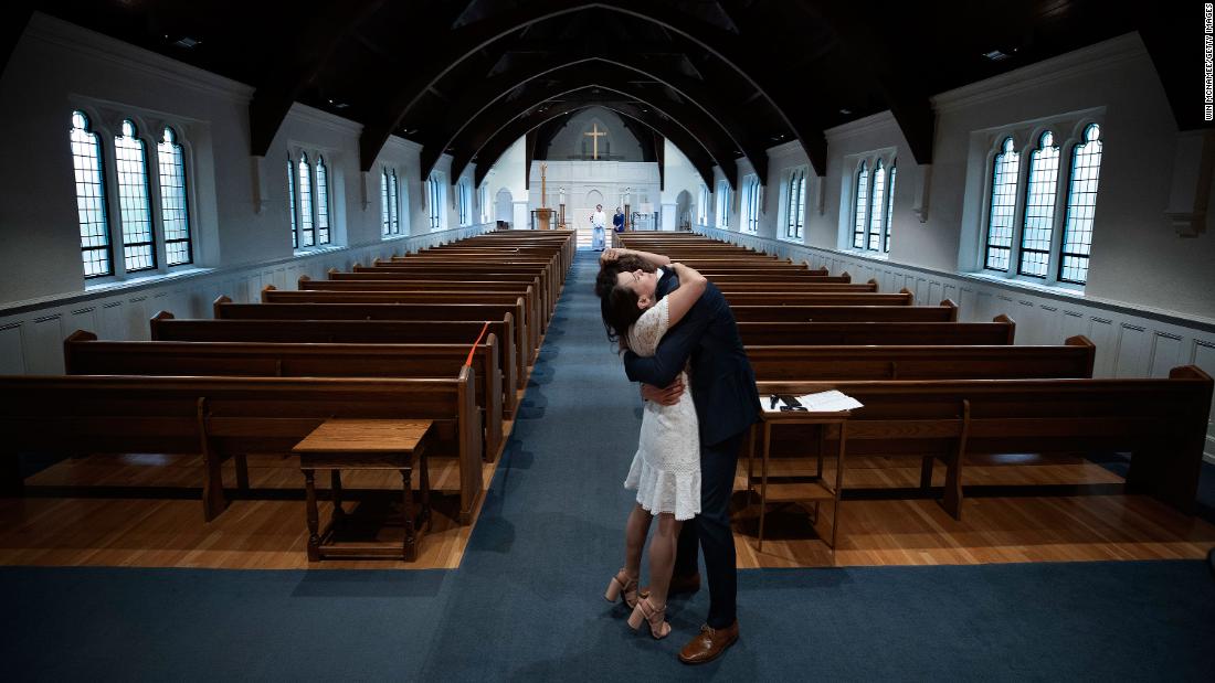 Newly married Tyler and Caryn Suiters embrace following their marriage ceremony in Arlington, Virginia, on April 18, 2020. The Rev. Andrew Merrow and his wife, Cameron, were the only other attendees at the ceremony, which was held at St. Mary&#39;s Episcopal Church.