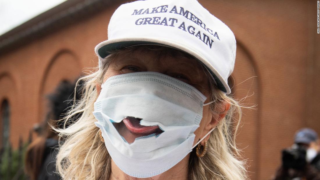 A woman sticks her tongue out of a torn mask at a Reopen Maryland rally outside the State House in Annapolis, Maryland, on April 18, 2020. Residents in multiple states were protesting stay-at-home orders.