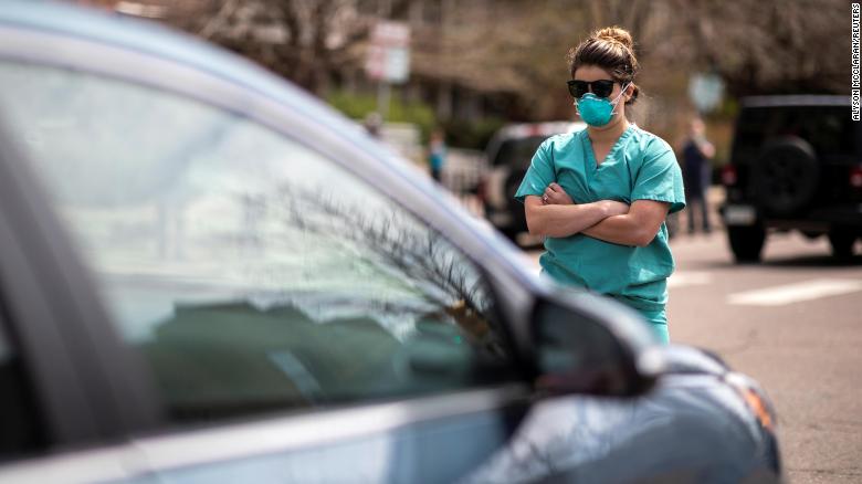 A health care worker  counterprotests at a rally demanding Colorado ease its stay-at-home order.