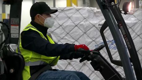 At the warehouse, a team of around 50 people moved quickly to remove tarps, take the individual boxes of items out of the larger packaging, combine the boxes, and move them to a trucking dock to ship them off to their next destination. 