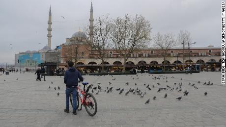 A man with his bike surrounded by pigeons in a nearly empty Yenicami Square, at the Spice Bazaar in Istanbul, Turkey, during the weekend lockdown.